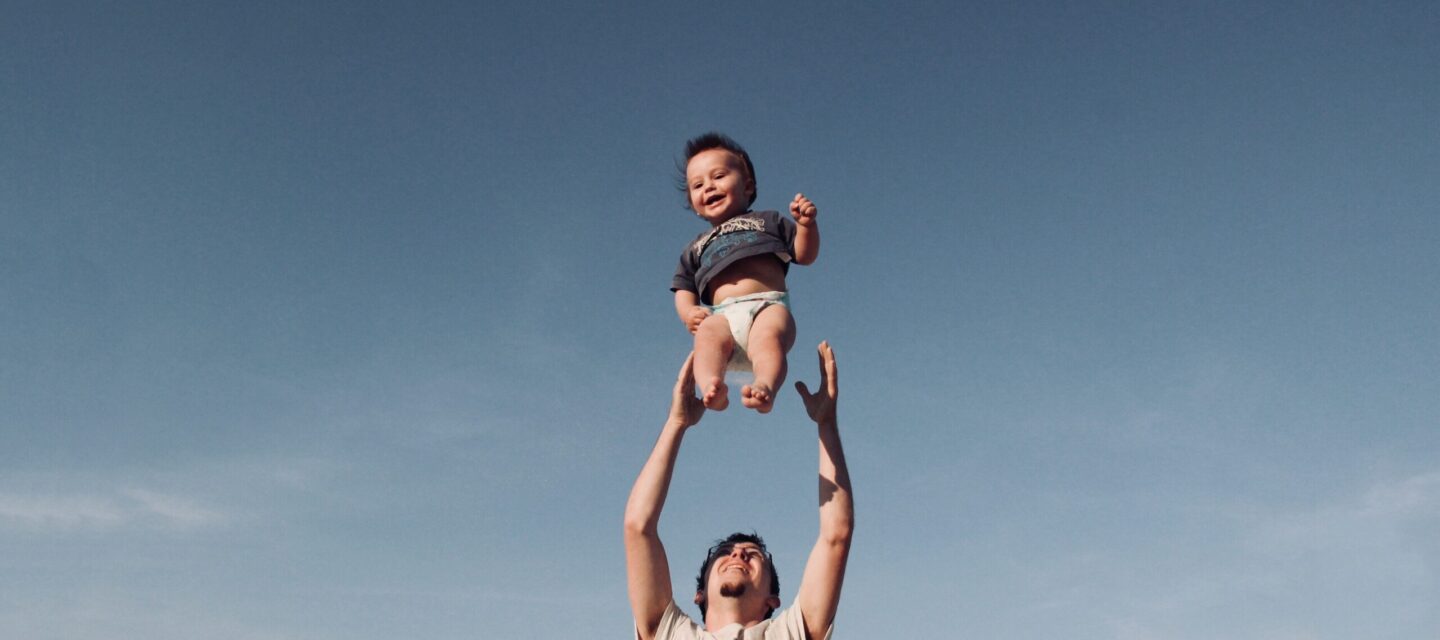 photo-of-man-in-raising-baby-under-blue-sky-1166990