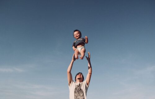 photo-of-man-in-raising-baby-under-blue-sky-1166990